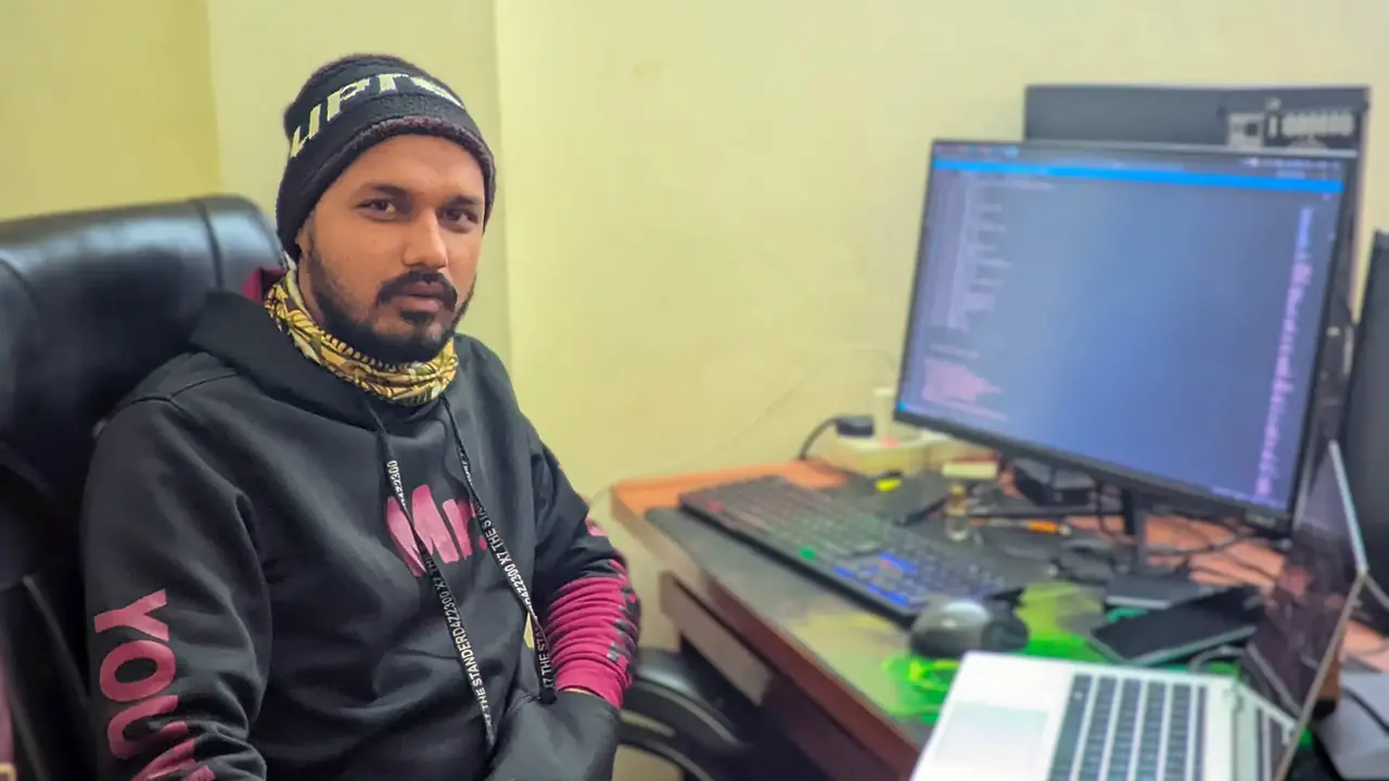 A developer working at a desk with a monitor beside him