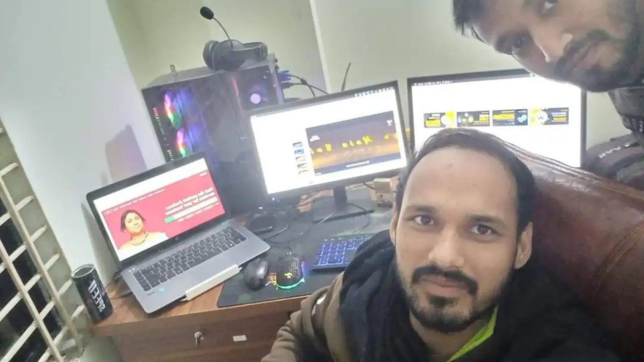 Two team members at a workstation with several screens